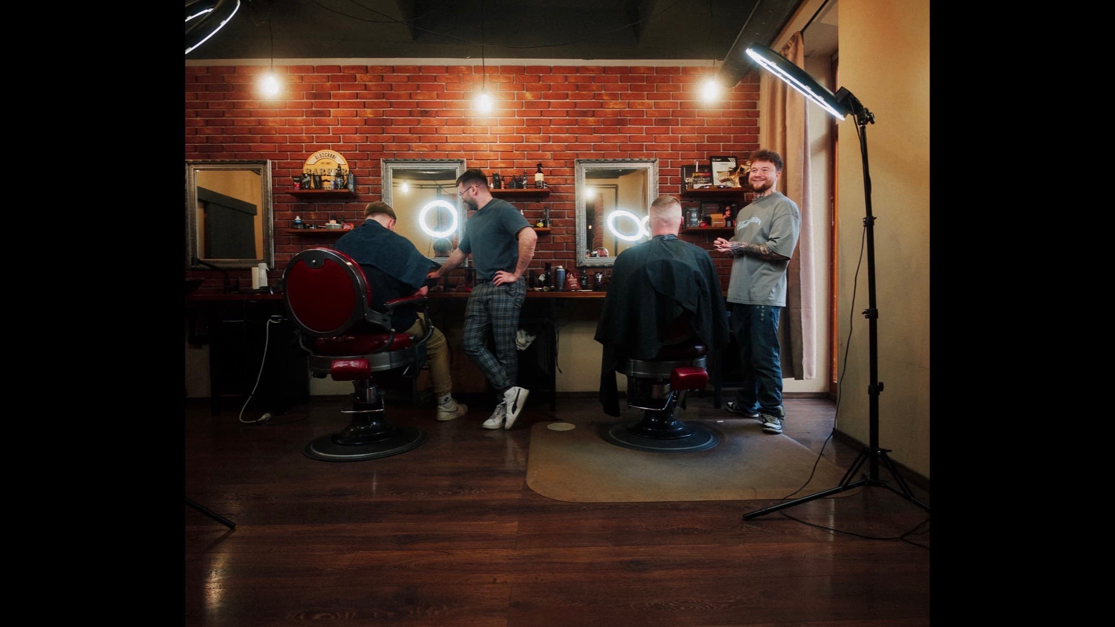 Interiér Oldschool Barber Shop — dve barberské kreslá, tehlová stena